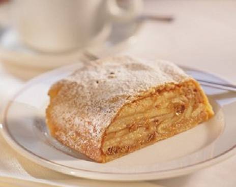 A slice of apple strudel on a plate with coffee. The image represents the package dinner and concert