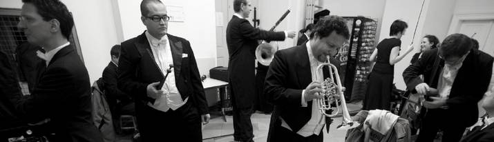 The photo depicts musicians of the Schoenbrunn Palace Orchestra in the waiting area of the Orangery while warming up for the concert