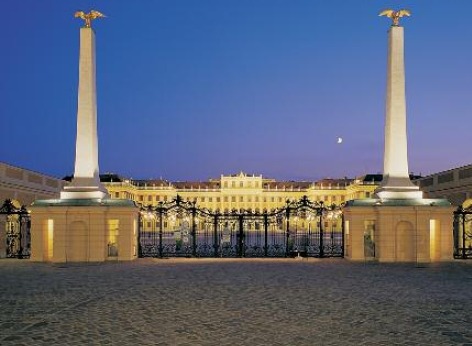 Nello sfondo c’è il castello di Schönbrunn illuminato. Davanti si vede un portone di ferro chiuso con entrambi i montanti